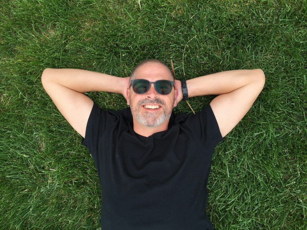 A happy man lying in the grass.