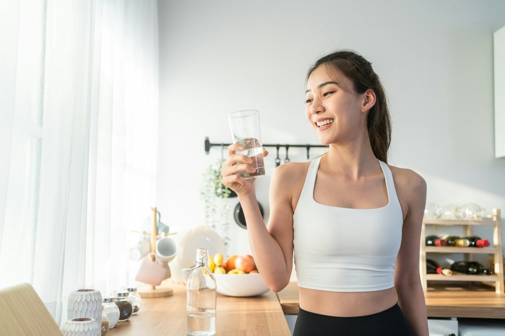 Asian beautiful woman in sportswear drink water after exercise at home.