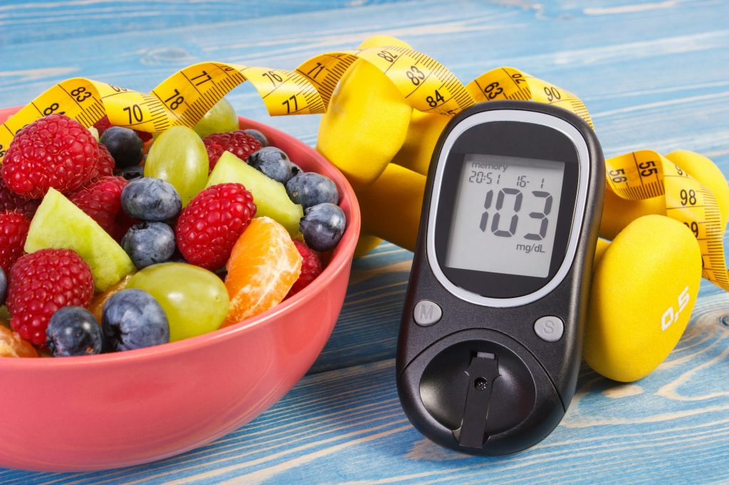 Fruit salad, glucose meter, centimeter and dumbbells