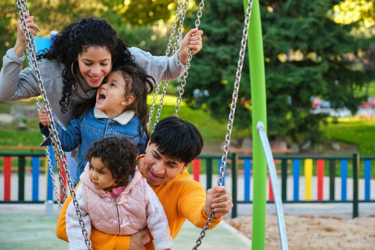 Latin family with two children playing together in a playground.