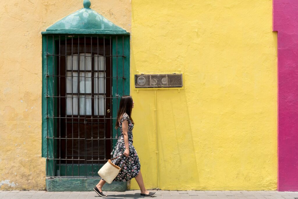 Woman in a dress in front of a colorful wall in Mexico