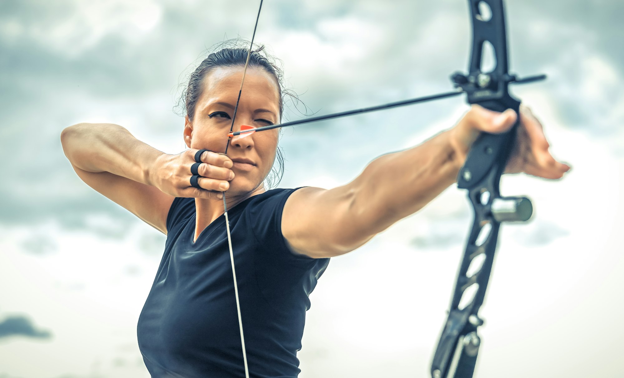 attractive woman on archery, focuses eye target for arrow from bow. cinema form