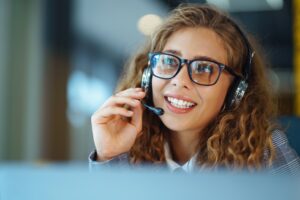 Call center agent with headset working on support hotline in modern office. Video conference.